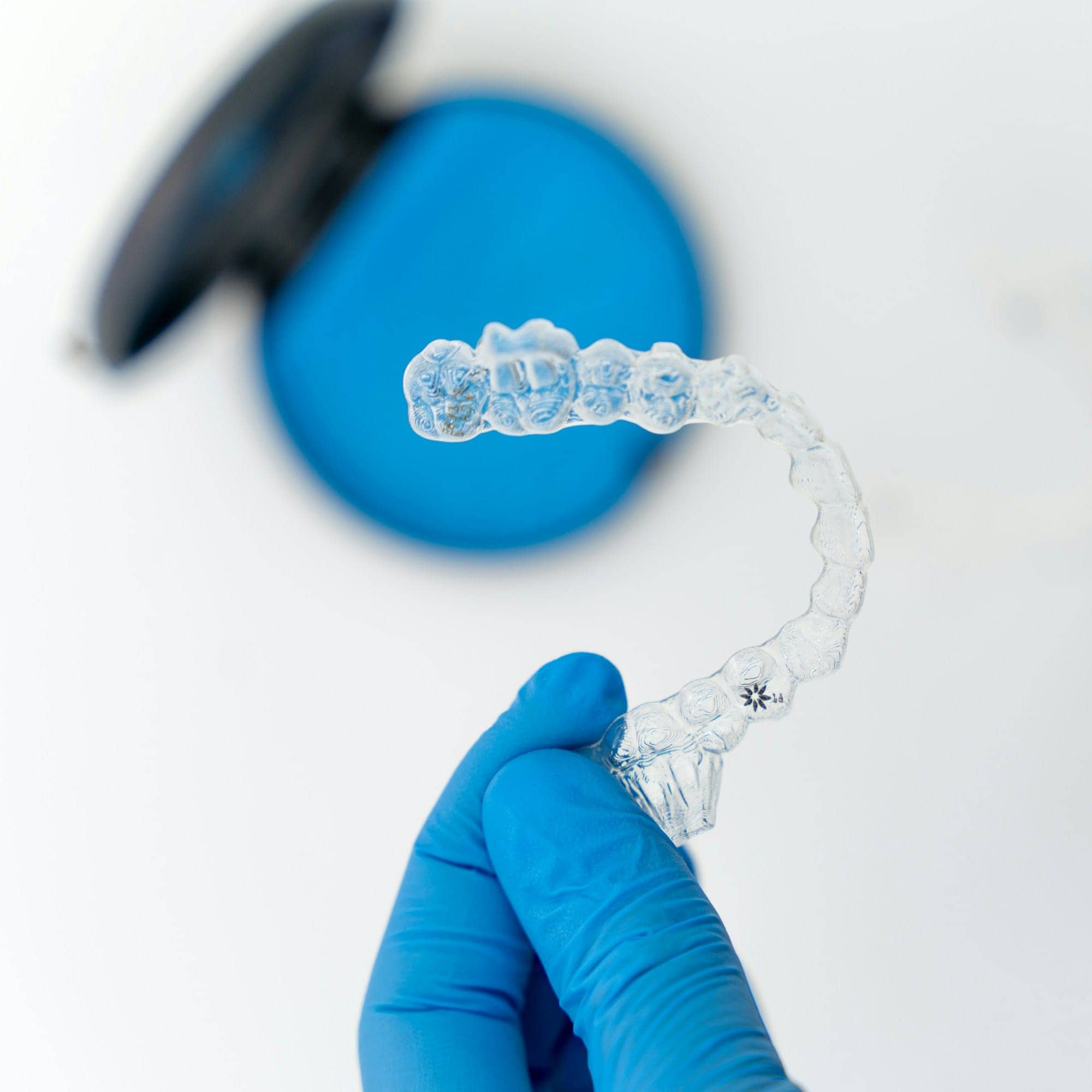 Gouttière transparente tenue par une main gantée